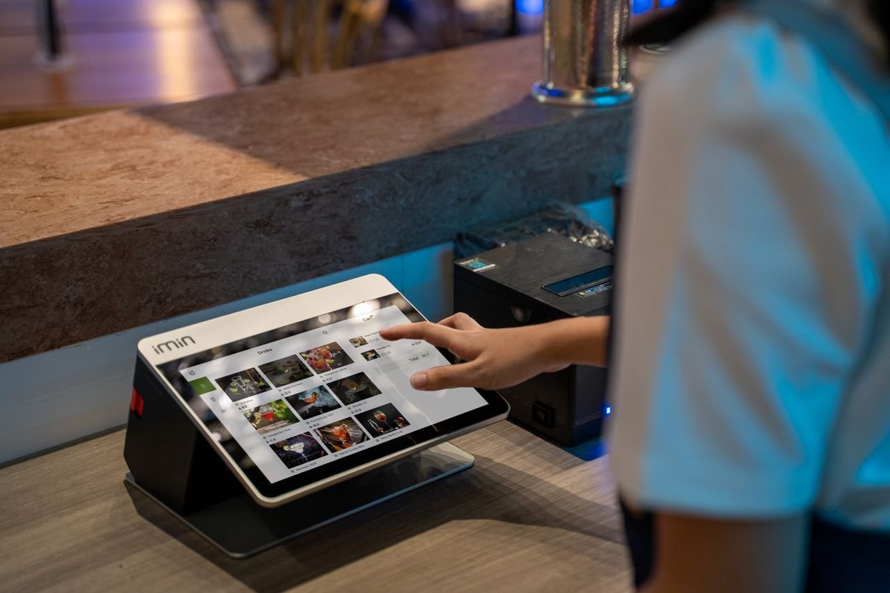 programs-01 A close-up of a person interacting with a touchscreen in a restaurant setting, showcasing modern technology.